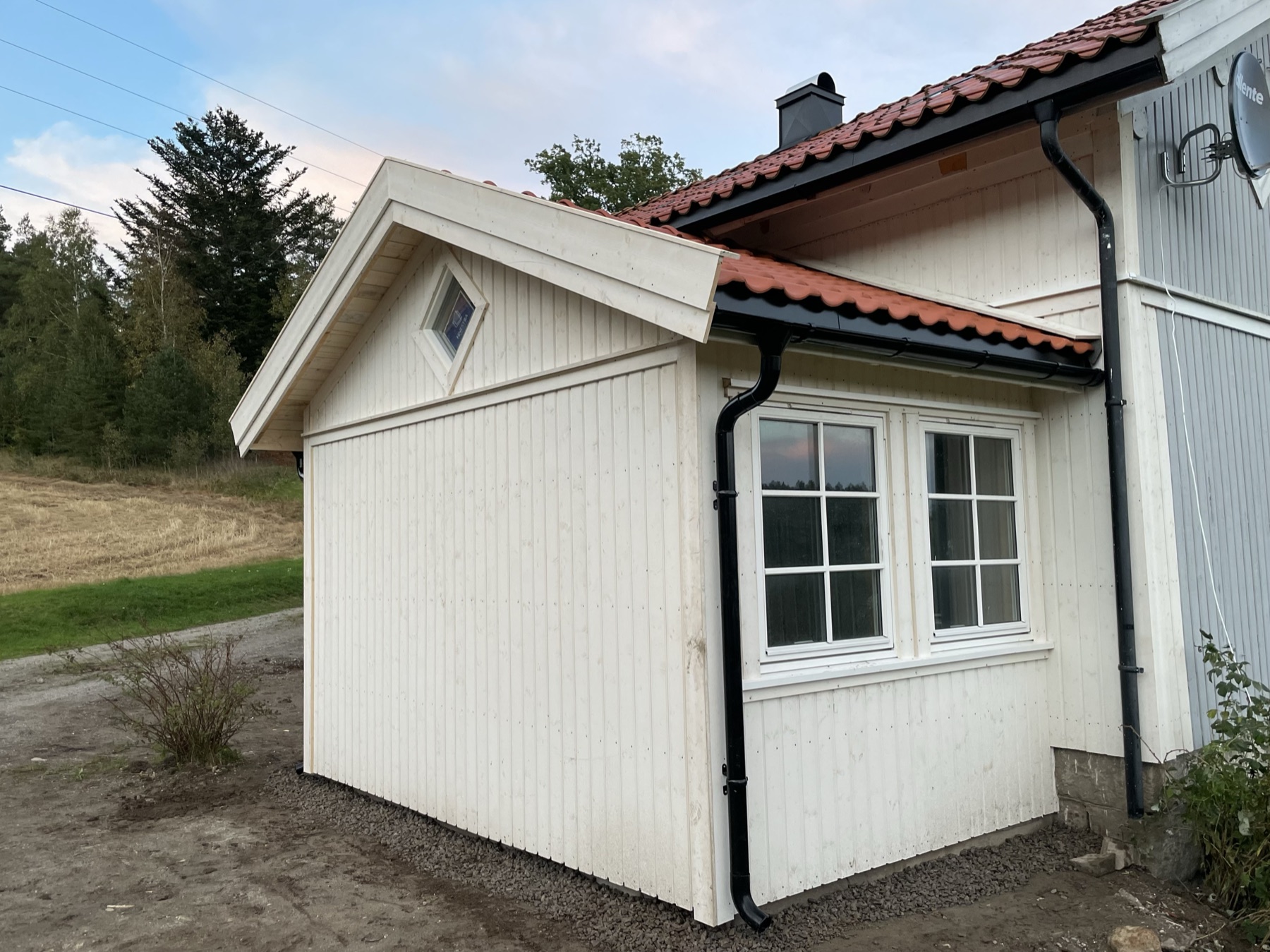 Tilbygg med hvit kledning, nye vinduer og teglsteinstak